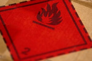 Spedire un pacco a Londra con SpedizioneComoda.it 3 Un'etichetta rossa con simbolo di fiamma su un pacco di cartone richiama gli articoli proibiti da spedire e i rischi legati a merci infiammabili.